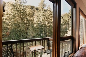 A balcony with a table and chairs, overlooking a forested area. - Mt Baker Lodging Condo 55sw - Sleeps 4, Great Community Aemenities (Deming)