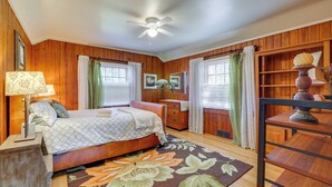 A bedroom with a bed, a dresser, a nightstand, a lamp, a ceiling fan, and a window with curtains. - Unwind Fireside & Walk to Dtwn! Tyron Retreat (Tryon)