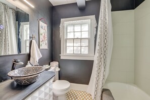 A bathroom with a black and white patterned sink, a white toilet, a window with a white curtain, and a shower area. - Unwind Fireside & Walk to Dtwn! Tyron Retreat (Tryon)