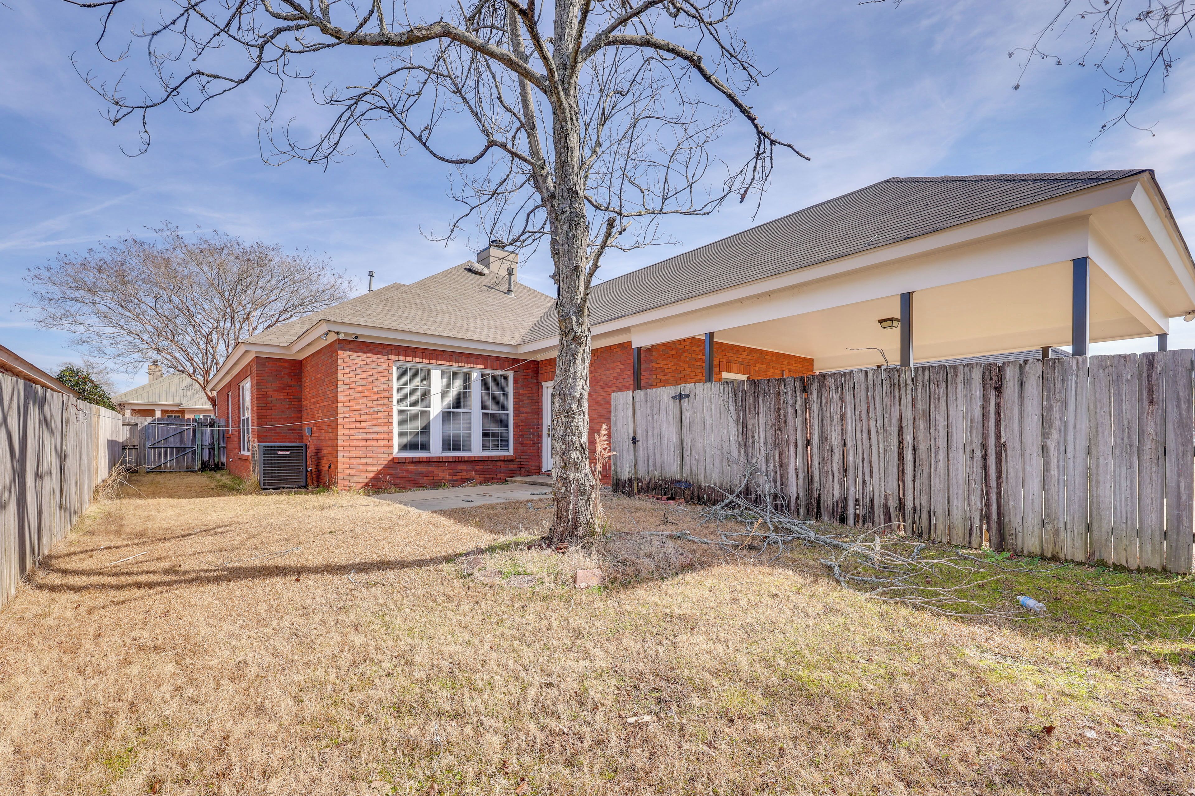 A residential property with a brick house, a wooden fence, and a yard with dry grass.
