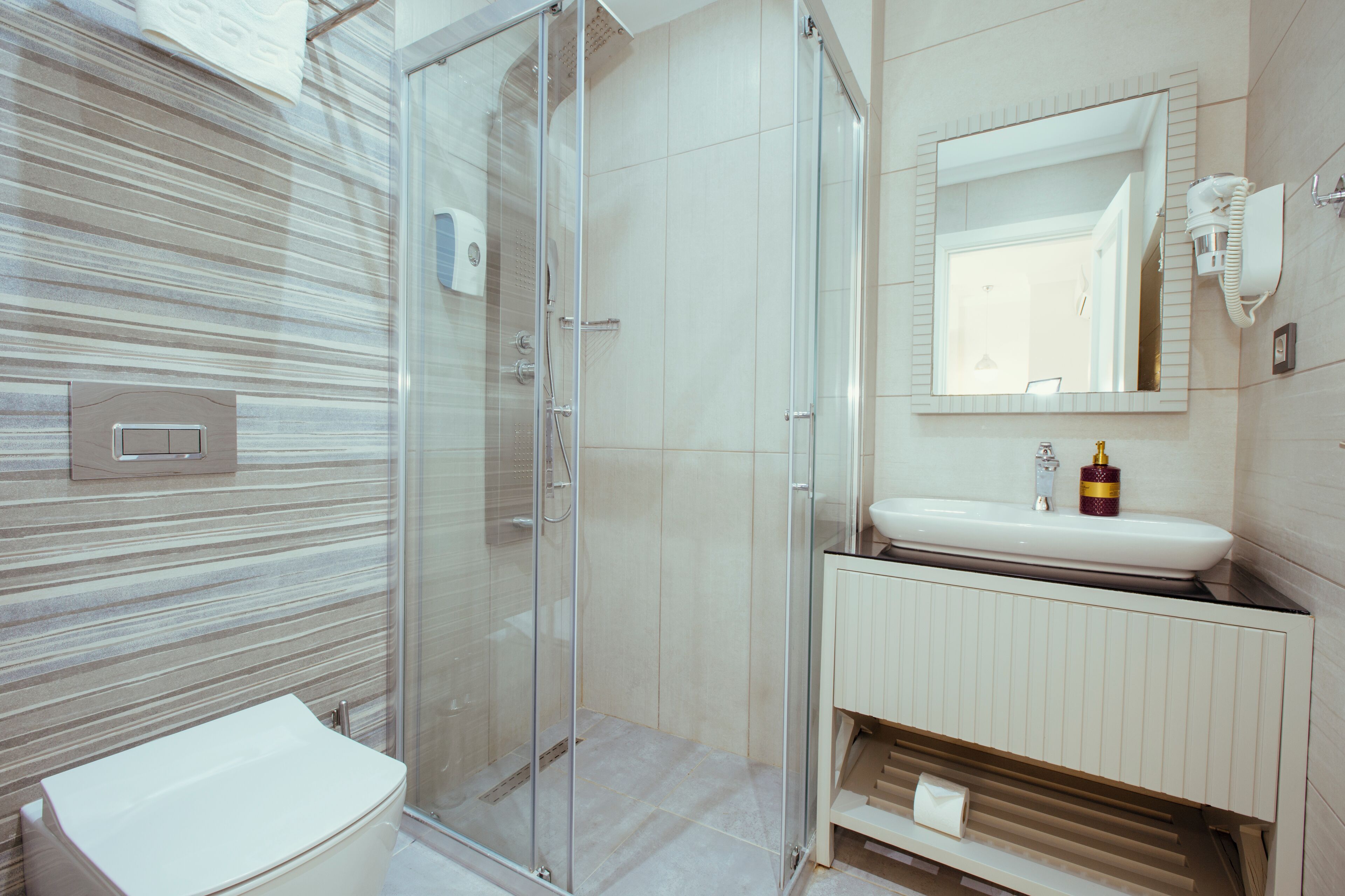 A modern bathroom with a glass shower enclosure, a white sink, and a mirror above the sink.