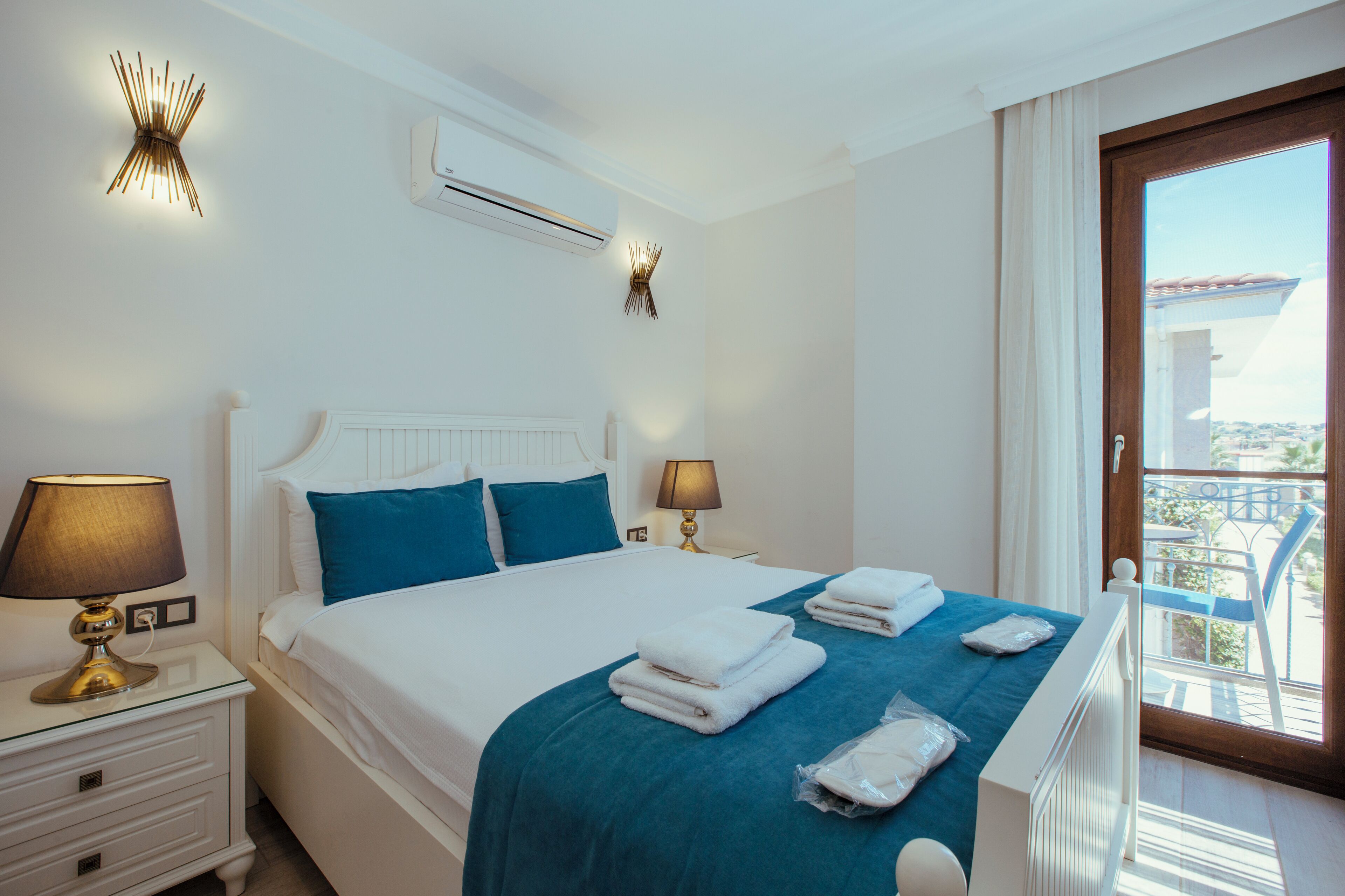 Een hotelkamer met een bed, twee bedlampen, een raam met uitzicht en een plafondventilator.