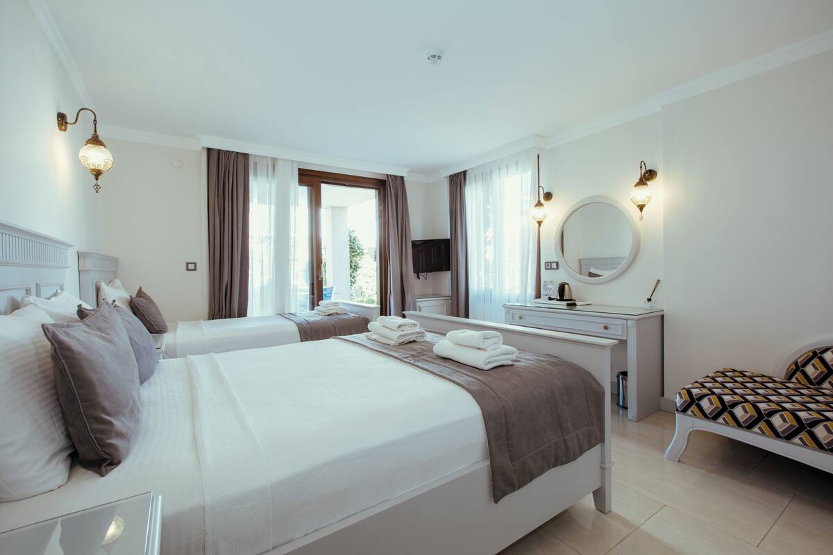 A hotel room with two beds, a desk, a mirror, and a TV.