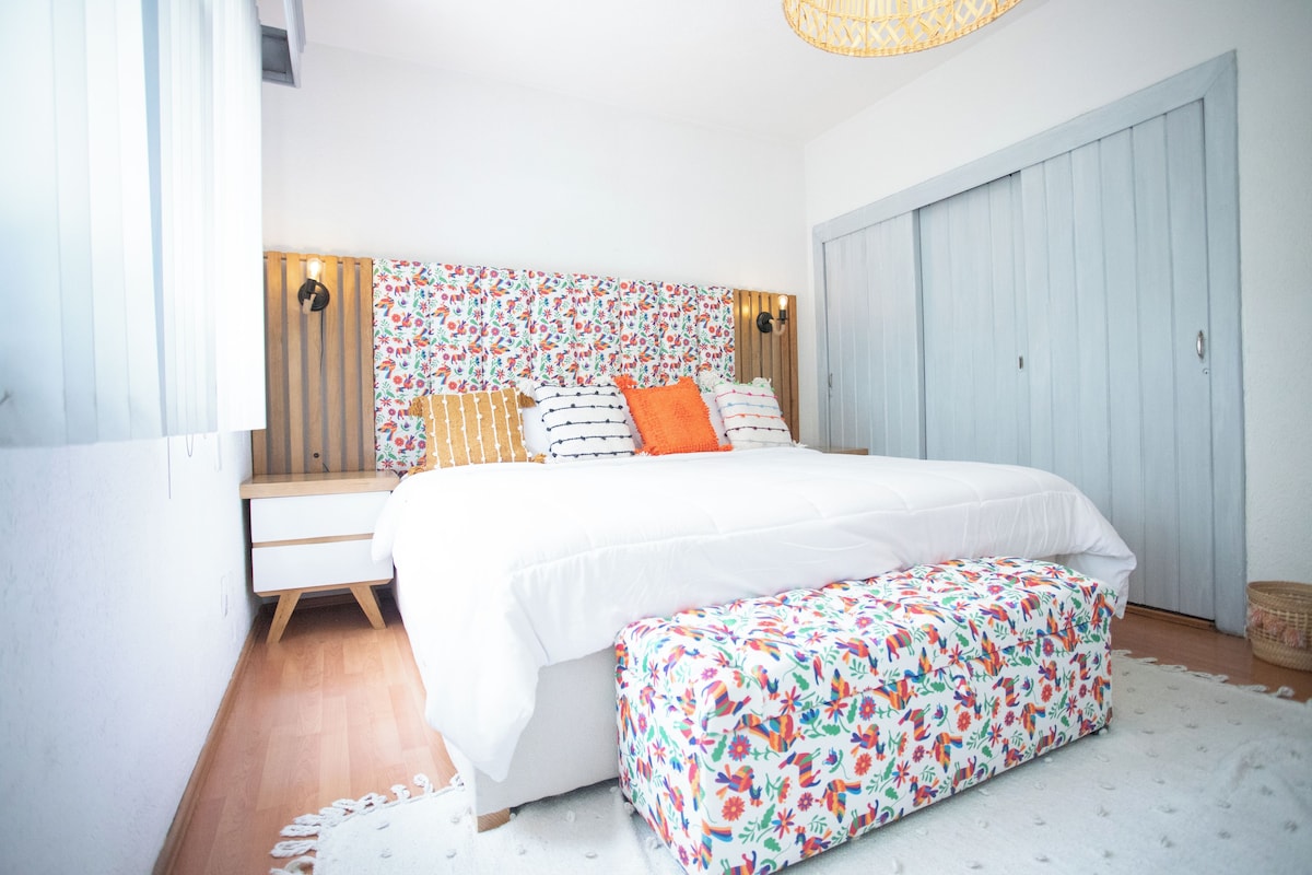 Un dormitorio con cama, mesita de noche, banco y armario.
