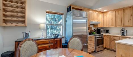 Una cocina moderna con armarios de madera, electrodomésticos de acero inoxidable y un comedor con mesa y sillas.
