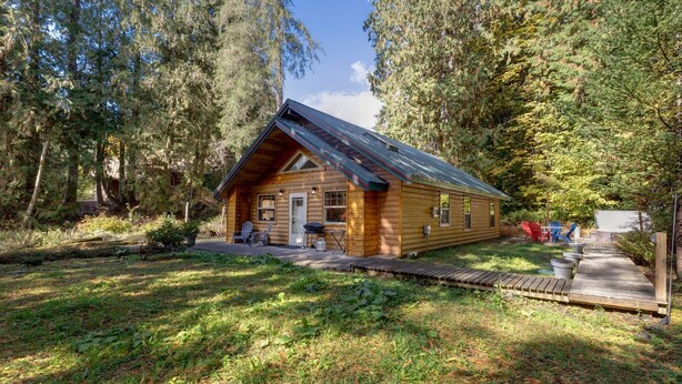 Une cabane en bois, dotée d’un toit en pente, entourée d’une forêt dense.