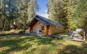Een houten chalet met schuin dak, omringd door dicht bos.
