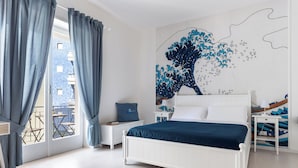 A bedroom with a bed, a nightstand, a wall mural, and a view of the outside balcony.