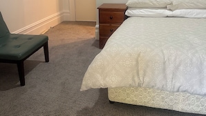 A hotel room with a bed, a chair, a nightstand, and a door. - Woolpack Hotel (Parramatta)