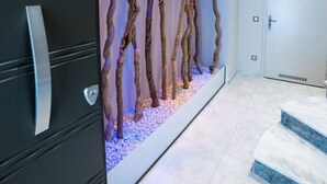 A modern bathroom with a unique wall art installation of twisted branches, a large mirror, and a sleek black cabinet.