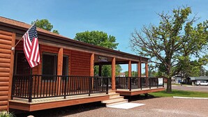 Eine Holzhütte mit Veranda, einer US-amerikanischen Flagge und einem Willkommensschild.