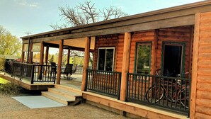 Eine Holzhütte mit verdeckter Veranda, Sitzgelegenheiten im Freien und Fahrrädern.