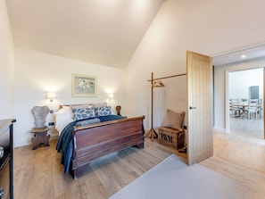 Una camera da letto con un letto di legno, lampade sui comodini, un quadro, un armadio e un cesto di vimini.