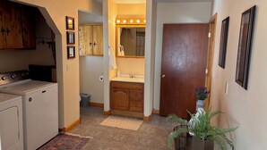 A compact kitchen with a stove, a small trash bin, and a wooden cabinet.
