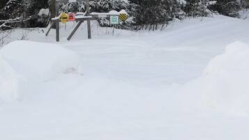 A snowy landscape with a wooden signpost indicating a no-entry and no parking zone.