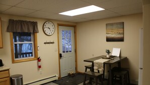 A small office with a clock, a window with a view, a door, a table with chairs, and a fire extinguisher.