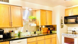 Una cocina con armarios de madera, un lavamanos de acero inoxidable, un microondas y una estufa.