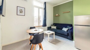 A compact living space with a dining area, a sofa, and a refrigerator. - Cosy, quiet, air-conditioned T2 apartment (Villeurbanne)
