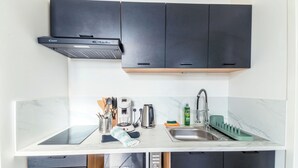 A modern kitchen with dark cabinets, a built-in stove, and a sink with a dish rack. - Cosy, quiet, air-conditioned T2 apartment (Villeurbanne)