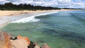 Una platja amb aigua cristal·lina, sorra daurada i roques a la vora.