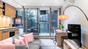 Un appartement moderne comprenant une cuisine, un coin repas, un salon avec canapé et un balcon offrant une vue sur la ville.