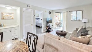 A compact living space with a dining area, a sofa, a television, and a view to a balcony. - BEAUTY on The Sound!  Port Royal Hilton Head, Gorgeous, Peaceful Sleeps 6/2br2ba (Hilton Head)