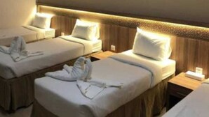 A hotel room with three single beds, each with a bedside table and lamp. - ASMA MAKKAH TAYSEER (Makkah)