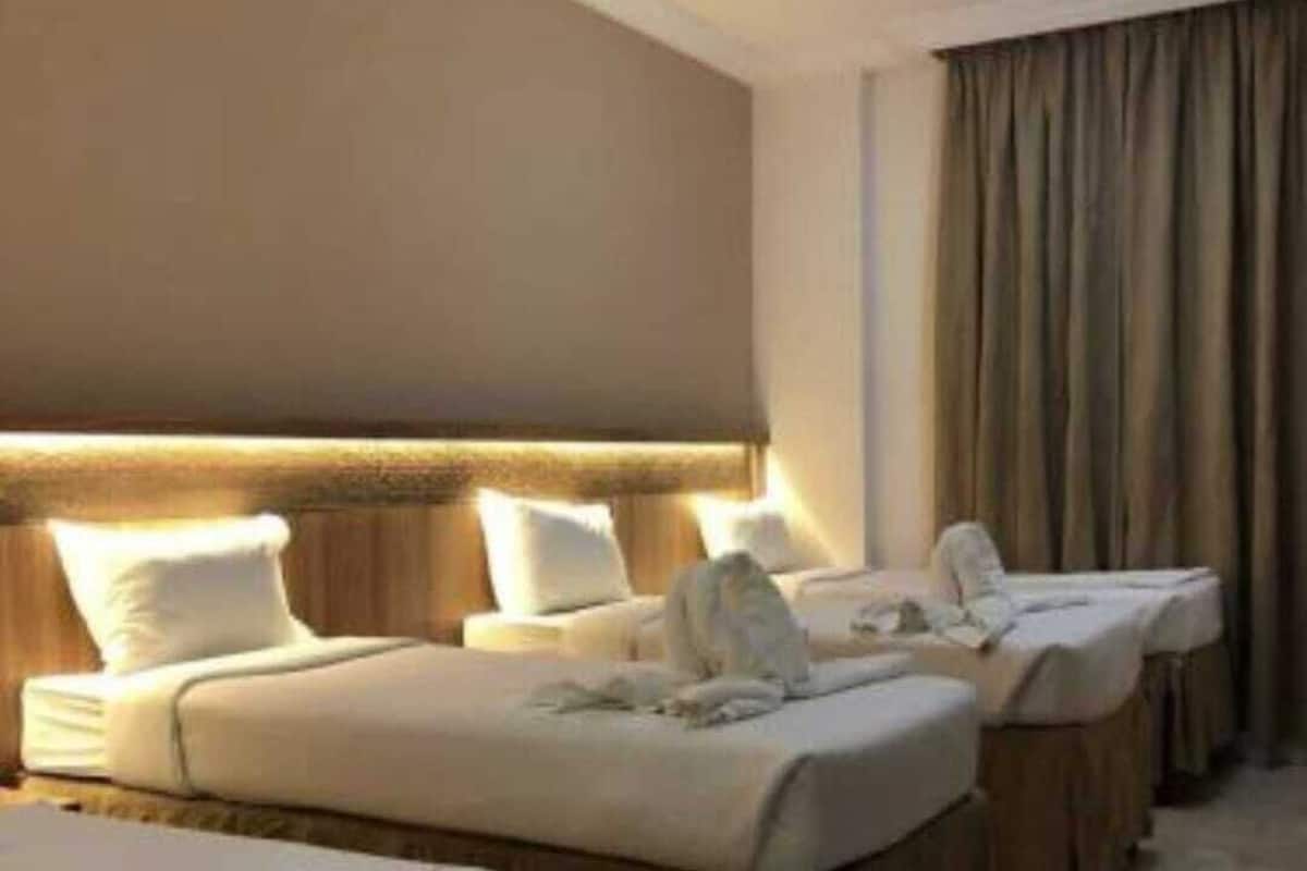 A hotel room with a large bed, two smaller beds, and a separate sofa.