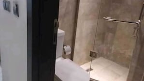A bathroom with a toilet, a shower, and a glass door. - ASMA MAKKAH TAYSEER (Makkah)