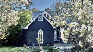Une maison bleu foncé, dotée d’un toit à pignon et d’une seule fenêtre en arc.