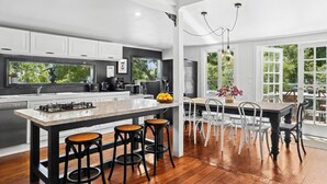 Une cuisine moderne dotée d’un grand îlot central, de tabourets de bar et d’un coin repas avec des chaises blanches.
