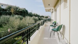 A balcony with a railing, a table with chairs, and a potted plant. - Aelia Prime Experience 3 (Kos)