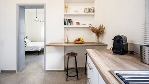 A compact kitchen with a wooden countertop, a coffee machine, and a small bar stool. - Coastal Elegance Suite 1Min to the Beach (Kos)