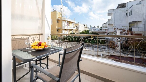A balcony with a table set for two, a chair, and a bowl of fruit. - Coastal Elegance Suite 1Min to the Beach (Kos)