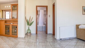 A spacious living area with a wooden cabinet, a potted plant, a radiator, and a doorway leading to a bathroom. - Beachside Retreat Steps to Kos (Kos)
