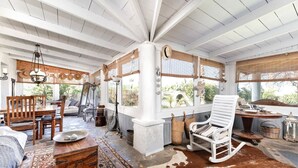 A spacious room with a high ceiling, large windows, and a rustic decor featuring wooden furniture and a cowhide rug. - Paradiso Vintage Villa: Traditional 1944 Gem (Pili)