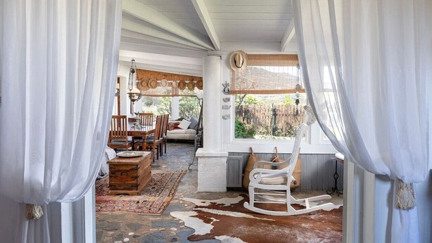 A rustic interior with a wooden dining table, chairs, a rocking chair, and a cowhide rug. - Paradiso Vintage Villa: Traditional 1944 Gem (Pili)