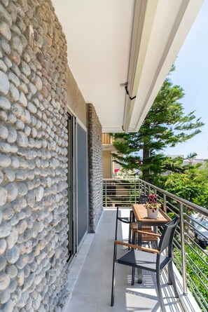 A balcony with a stone wall, a table with chairs, and a railing overlooking a residential area. - Blue Waters Premium Suite | Kos (Kos)