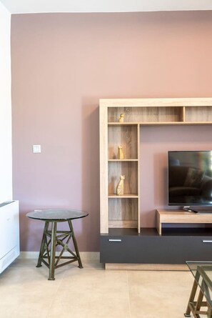 A modern living room with a wooden entertainment unit, a glass table, and a flat-screen TV.
