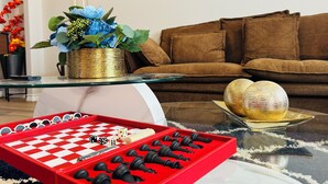 A living room with a glass coffee table, a chessboard, and a decorative plant. - Charming & Cozy in the Heart off LubbockPerfect forYour Getaway Close toTex Tech (Lubbock)