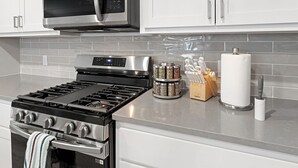 A modern kitchen with stainless steel appliances, a gas stove, a microwave, and a spice rack. - Charming & Cozy in the Heart off LubbockPerfect forYour Getaway Close toTex Tech (Lubbock)
