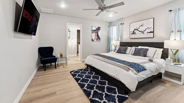 A modern bedroom with a bed, a chair, a ceiling fan, and artwork on the walls. - Charming & Cozy in the Heart off LubbockPerfect forYour Getaway Close toTex Tech (Lubbock)