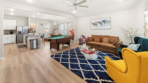 A modern living room with a pool table, a sofa, and a yellow armchair. - Charming & Cozy in the Heart off LubbockPerfect forYour Getaway Close toTex Tech (Lubbock)