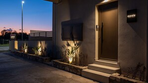 A modern building with a well-lit entrance, a nameplate, and a small outdoor seating area with plants. - Beach Luxury Homes : Nicole (Kos)