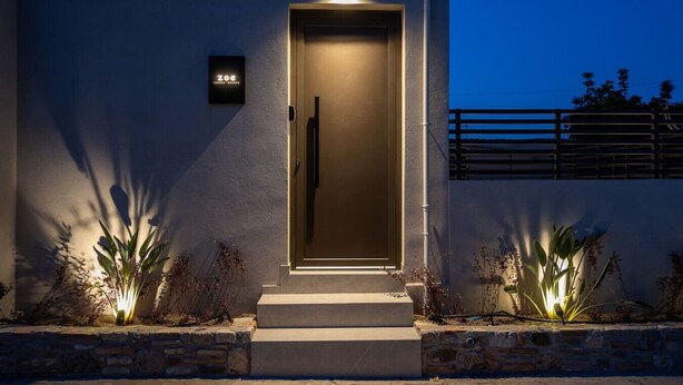A modern building with a well-lit entrance, a visible door, and a small sign above the door. - Beach Luxury Homes : Zoe (Kos)