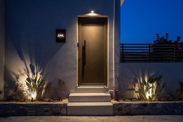 A modern building with a well-lit entrance, a visible door, and a small sign above the door.