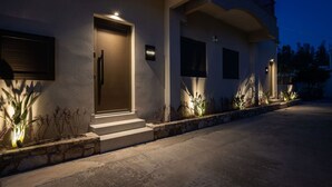 A modern building with a well-lit entrance, a stone pathway, and a signboard. - Beach Luxury Homes : Zoe (Kos)