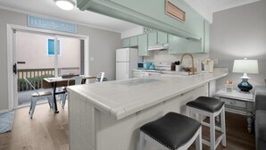 Una cocina con una isla central, armarios blancos y vistas al exterior.