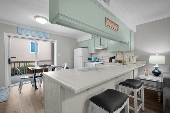 A kitchen with a central island, white cabinets, and a view to the outside.