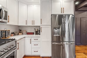 A modern kitchen with white cabinetry, stainless steel appliances, and wooden handles.